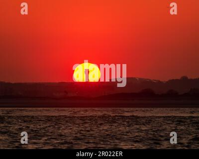 Tramonto dietro la torre di controllo dell'aeroporto di Dublino da Burrow Beach con polvere sahariana nell'atmosfera Foto Stock