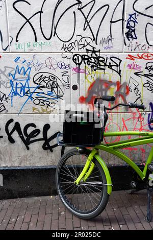 Tipica scena di Street art di Amsterdam con graffiti e biciclette parcheggiate Foto Stock