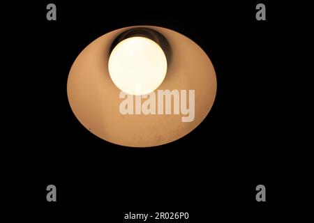 Una lampadina illuminata in una stanza con luce scura Foto Stock