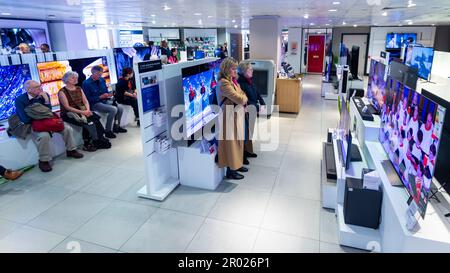 Londra, Regno Unito. 6 maggio 2023. La gente guarda l'incoronazione di Re Carlo III e della Regina Camilla su televisori a grande schermo presso il grande magazzino John Lewis di Oxford Street. Questa è la prima incoronazione del Regno Unito in 70 anni e la prima ad aver luogo nell’era digitale. Credit: Stephen Chung / Alamy Live News Foto Stock