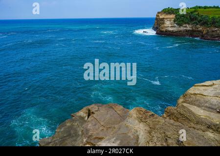 Pantai Klayar o Klayar Beach con rocce e onde forti contro il cielo blu. Sfocatura del movimento. Fotografia di paesaggi. Foto Stock