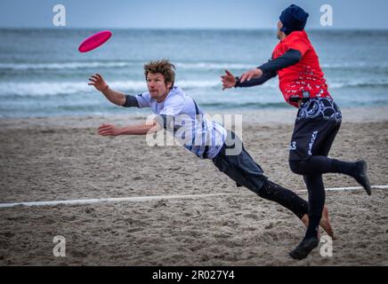 Rostock, Germania. 06th maggio, 2023. Al quinto Campionato tedesco Mixed Beach in beach frisbee, le squadre di Rotpot Braunschweig (bianco) e Funatics Hannover (rosso) giocano l'una contro l'altra sulla spiaggia del Mar Baltico di Warnemünde. Nelle competizioni, cinque giocatori per squadra cercano di ottenere il frisbee nella zona finale della metà dell'avversario. Un totale di 24 squadre con 200 giocatori provenienti da tutta la Germania giocano per il campionato tedesco. Credit: Jens Büttner/dpa/Alamy Live News Foto Stock