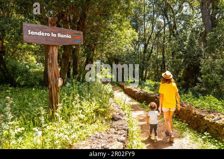 Una madre con suo figlio accanto ad un cartello che identifica il sentiero la Llania a El Hierro, Isole Canarie. lussureggiante paesaggio verde Foto Stock