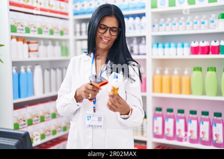 Età media donna ispanica farmacista pillole scansione flacone in farmacia Foto Stock