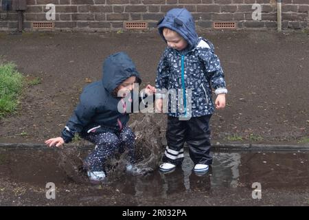 Windsor, Berkshire, Regno Unito. 6th maggio, 2023. Divertimento nelle pozzanghere per due cucciolate al Bexley Street Coronation party. Credit: Maureen McLean/Alamy Live News Foto Stock