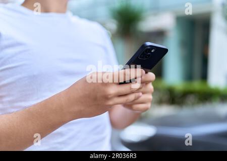 Uomo non binario che utilizza lo smartphone per strada Foto Stock