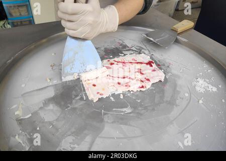 Primo piano su un gelato fritto in preparazione su una padella. Conosciuto anche come gelato arrotolato, è un dessert zuccherato congelato dalla Thailandia. Foto Stock