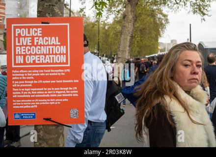 Incoronazione, Londra, 6 maggio 2023. Una donna guarda direttamente la telecamera accanto a un cartello della polizia metropolitana di Londra che annuncia l'uso della tecnologia di riconoscimento facciale dal vivo durante l'incoronazione di Re Carlo III L'uso di questa tecnologia è controverso e solleva interrogativi sulla privacy e sulle libertà civili nell'era delle nuove tecnologie. Sottolinea inoltre le tensioni tra il mantenimento della sicurezza pubblica e la tutela dei diritti individuali in un mondo in evoluzione. Credito: Andy Soloman Foto Stock