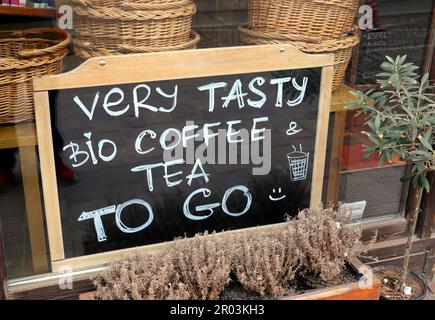 Lavagna con testo: Molto gustoso bio caffè e tè da andare alla finestra del bar. Foto Stock