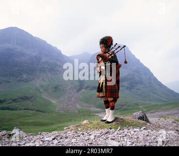 Scozia. Highlands. Piper scozzese nel paesaggio. Foto Stock