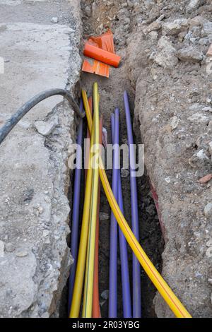 Molti cavi di comunicazione protetti in tubi di vari colori. installazione di infrastrutture sotterranee. Cantiere con elettrico e alta velocità Foto Stock