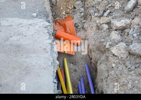 Molti cavi di comunicazione protetti in tubi di vari colori. installazione di infrastrutture sotterranee. Cantiere con elettrico e alta velocità Foto Stock