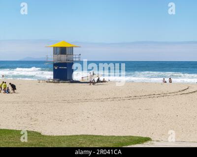 Tauranga Nuova Zelanda - Febbraio 12 2011; Surf-salvavita torre di guardia sulla spiaggia principale con giovani uomini che trasportano tavole da surf Foto Stock