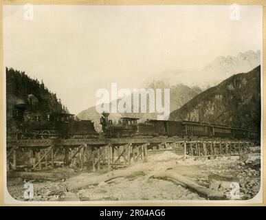 White Pass e Yukon treno ferroviario che attraversa il fiume Skagway, 21 ottobre 1898. Durante la corsa all'oro di Klondike, il Passo Bianco era una delle rotte usate dai cercatori per viaggiare da Skagway ai campi d'oro di Yukon. Nell'aprile del 1898, la White Pass and Yukon Railroad Company è stata fondata nel tentativo di stabilire un percorso più facile attraverso il passaggio. La costruzione della ferrovia iniziò il mese successivo. Migliaia di lavoratori hanno lavorato 24 ore su 24 in condizioni infide per completare il progetto. La ferrovia fu completata al Passo Bianco il 20 febbraio 1899 e raggiunse il Lago Bennett il 6 luglio 1899. Foto Stock