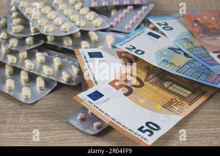 Immagine simbolica per il costo elevato della medicina con le pillole sul denaro Foto Stock