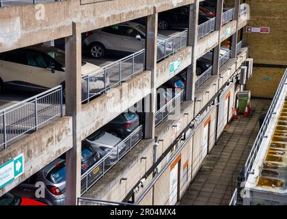 Una gamma colorata di auto parcheggiate su più piani in un moderno garage, che offre una varietà di opzioni di trasporto Foto Stock