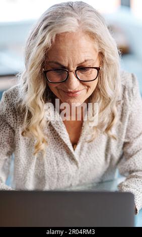 La sua non solo casa, è una zona produttiva. una donna d'affari senior attraente che utilizza un notebook mentre lavora da casa. Foto Stock