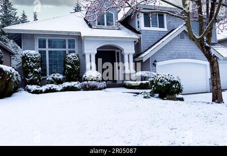 Tempesta di neve all'inizio della primavera con casa e cortile coperto di neve bianca Foto Stock