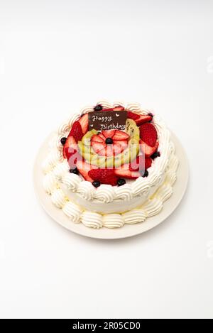 Torta di compleanno fatta in casa decorata con fragole, kiwi e mirtilli isolati su sfondo bianco nella vista dall'alto. Scatto verticale. Foto Stock