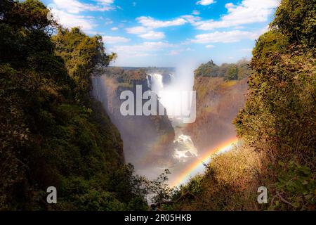 Un doppio arcobaleno si forma mentre il fiume Zambesi si immerge sulle spettacolari Cascate Vittoria in una gola che separa lo Zimbabwe dallo Zambia Foto Stock