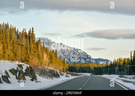 Splendido paesaggio invernale vicino a Whitehorse nel territorio dello Yukon, con enormi montagne innevate sulla strada per Atlin, British Columbia. Foto Stock