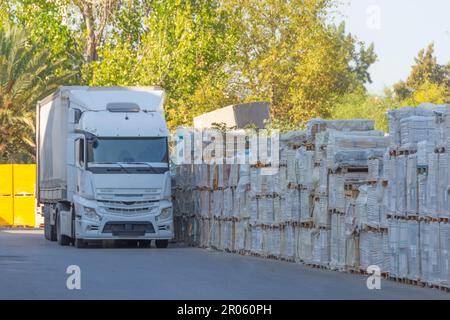 Autocarro di grandi dimensioni con rimorchio vicino a un magazzino con casse di carico diverso Foto Stock