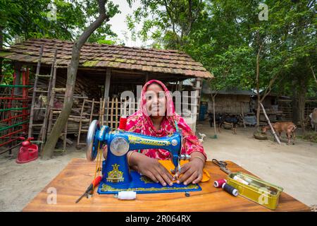 Bangladesh – 19 maggio 2019: Una donna di un villaggio di mezza età si siede nel cortile per cucire la sua famiglia a Jibannagar Upazila, nel distretto di Chuadanga. Foto Stock