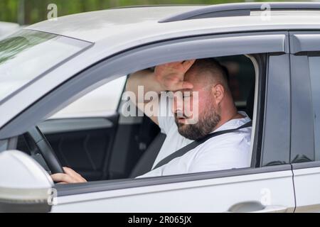 Uomo esausto in sovrappeso guida in auto senza aria condizionata in estate caldo tempo. Foto Stock