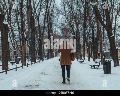 uomo in cappotto sul sentiero del parco cittadino in inverno Foto Stock