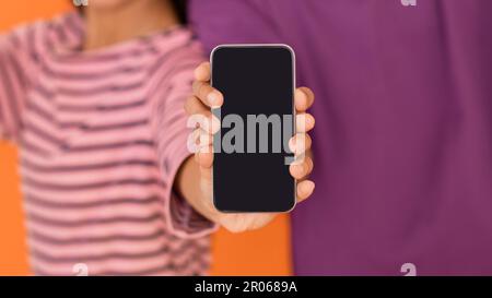 Coppia irriconoscibile che mostra lo smartphone con schermo nero, mockup Foto Stock