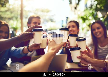 Che il caffè sia forte quanto l'amicizia. un gruppo di amici brinda con le tazze di caffè mentre fuori insieme. Foto Stock