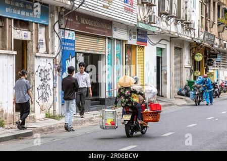 Signora vietnamita che indossa un cappello di bambù, una pannier e una moto, ho Chi Minh City, Vietnam Foto Stock