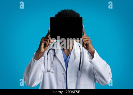 Medico afro-americano che tiene il tablet digitale sopra il suo volto Foto Stock
