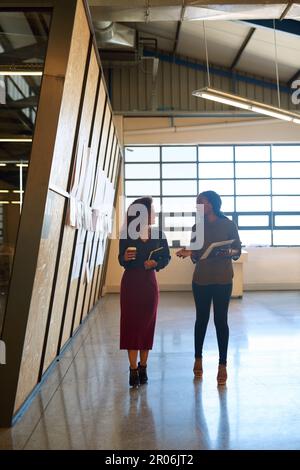 Comunicano bene tra loro. due donne d'affari che hanno una discussione mentre camminano attraverso un ufficio. Foto Stock