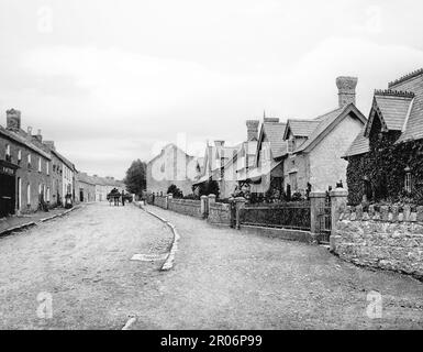 Una scena di strada di fine '19th con cavalli e cart oltre le case ALMS a Gowran, una città situata sul lato orientale della Contea di Kilkenny, Irlanda Foto Stock