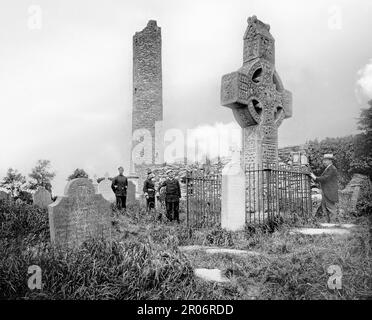 Una vista di fine 19th ° secolo dei visitatori che ammirano la Croce Ovest a Monasterboice un insediamento monastico paleocristiano nella Contea di Louth in Irlanda, a nord di Drogheda. Le tre croci alte sul sito monastico risalgono al 10th° secolo e fanno parte del gruppo scritturale, che mostra scene bibliche. La torre rotonda è alta circa 28 metri, probabilmente fu costruita poco dopo il 968 e danneggiata in un incendio nel 1098. Foto Stock