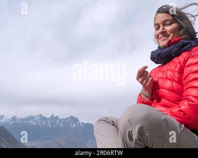Zaino in spalla femmina in Muktinath, Nepal, smilling a macchina fotografica con Himalaya in background. Foto Stock