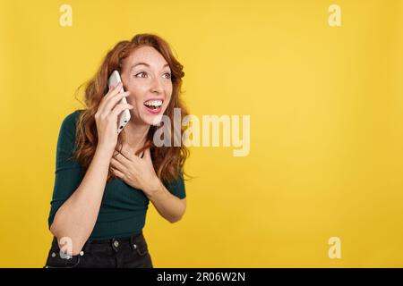 Donna redheaded che riceve buone notizie dal telefono cellulare Foto Stock