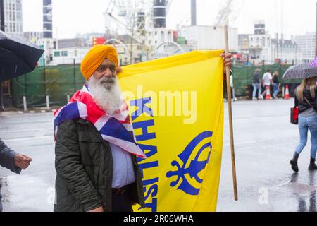 Londra, Westminster, Gran Bretagna. 06/5/2023 giorno dell'incoronazione. Un anziano sostenitore britannico Sikh del movimento Khalistan si ferma per una fotografia che tiene una bandiera colorata Sikh , Nishan Sahib lo stesso giorno Lord Indarjit Singh (Un Peer britannico Sikh) assume un ruolo di rappresentante chiave nella cerimonia di incoronazione del re Carlo III . Helen Cowles / Alamy Live News Foto Stock