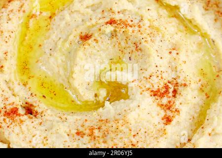 Vista dall'alto dell'hummus di ceci con olio d'oliva e paprika affumicata da vicino. Cibo vegano sano. Foto Stock