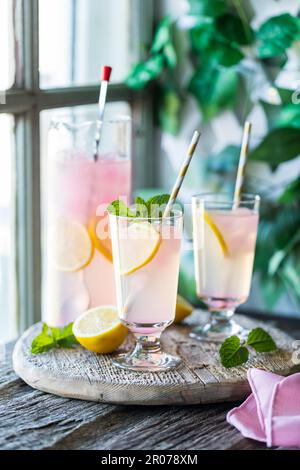 Bicchieri e caraffa di limonata rinfrescante su un rustico asse di legno. Foto Stock