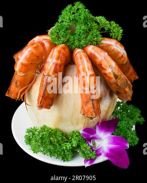 Gamberi d'arancia all'interno del cocco con salsa isolata su sfondo nero vista laterale Foto Stock