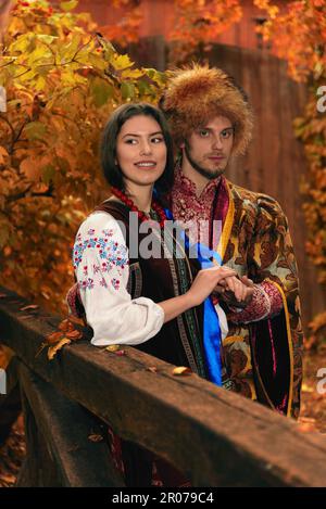 Giovane coppia vestito tradizionale ucraino abbigliamento. Uomo serio cossack e donna sorridente in costumi ricamati all'aperto. Vestito vintage Foto Stock