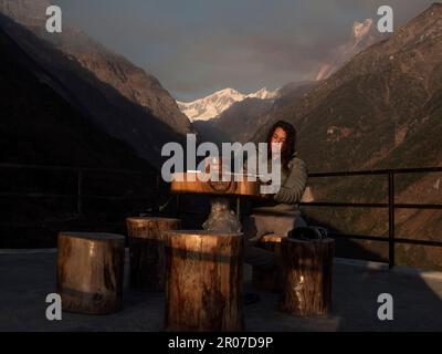 Vista frontale di una donna zaino in spalla sulla sua strada per Annapurna campo base scrivere le esperienze della sua giornata sul suo caseificio e Himalaya sullo sfondo. Foto Stock