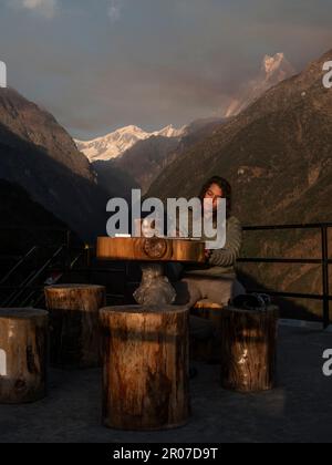 Vista verticale del backpacker brunette sulla sua strada per Annapurna campo base scrivere le esperienze del giorno sul suo caseificio e Himalaya sullo sfondo. Foto Stock