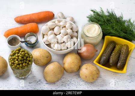 Ingredienti per un'insalata vegetariana Olivier: Patate, carote, funghi, cipolle, piselli verdi, aneto, salsa di maionese, sale e pepe nero su una luce Foto Stock