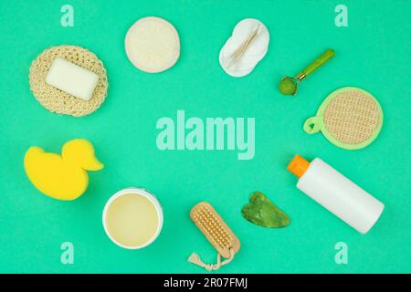 Salviette, crema, shampoo, gua sha e altri accessori su sfondo verde. Vista dall'alto. Copia spazio per il testo. Foto Stock