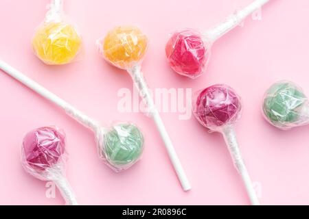 Lecca lecca colorata su sfondo rosa. Piano di giacitura, vista dall'alto Foto Stock