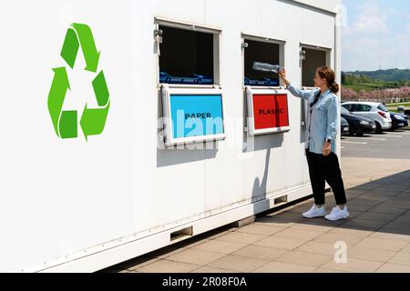 Separare la stazione di raccolta rifiuti sulla strada e la persona che getta rifiuti di plastica nel bidone dei rifiuti. Foto Stock