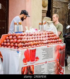 Marrakech, Marocco, 8 aprile 2023. Un venditore marocchino di sesso maschile che vende succo di melograno fresco ai turisti della medina di Marrakech. Foto Stock